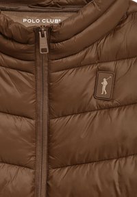 Chaqueta tipo puffer marrón con un collar alto, cremallera frontal y un acabado texturizado. Presenta un parche con un logotipo que representa una figura sosteniendo un palo de golf.