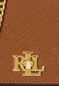 Geantă din piele texturată maro, cu un închizător în ton de aur cu logo-ul „RL” și o curea din lanț auriu. Materialul are un model subtil.