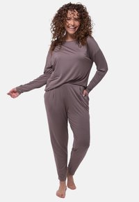 Brun loungeklädset med långärmad topp och byxor. Mjuk tyg med avslappnad passform och sidofickor. Texturerat, lätt material.