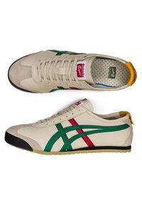 Beige Onitsuka Tiger sneakers with green and red side stripes, black toe cap, yellow heel tab, and white laces shown top and side views.