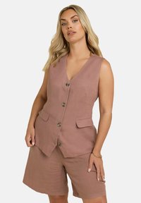 Gilet senza maniche in lino rosa chiaro con due tasche frontali e cinque bottoni. Abbinato a pantaloni corti coordinati, creando un insieme armonioso.