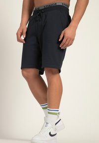 Marineblaue Sportshorts mit elastischem Bund und Kordelzug, kombiniert mit weißen Turnschuhen und gestreiften Socken.