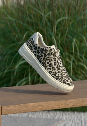 Baskets imprimé léopard avec une tige beige, bout rond et semelle blanche épaisse. Dotées d'œillets dorés et de lacets neutres sur un fond naturel.