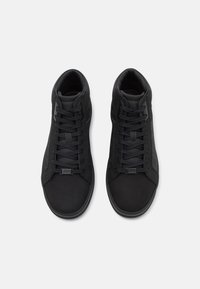 Sorte høyhælte sneakers i svart som har glatte syntetiske og semsket materialer, teksturerte detaljer og tradisjonelle snøringer.