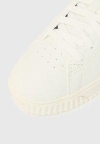 Άσπρο αθλητικό παπούτσι με λείο, συνθετικό επάνω μέρος, οπ ές κοντά στα δάχτυλα, επίπεδα λευκά κορδόνια και υφασμένο λαστιχένιο πάτο.