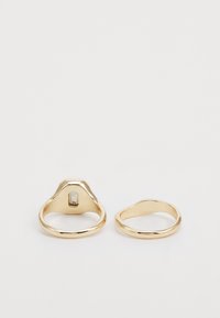Goldringe mit einem glatten Band, einer mit einer erhöhten rechteckigen Fassung und einem klaren Stein, der andere ein einfacher, schmuckloser Ring.