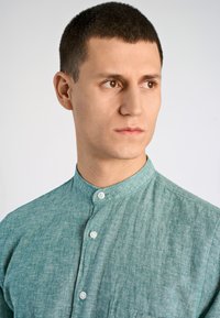 Lichtgroen, knoopsluiting overhemd met een bandkraag, gemaakt van gestructureerde stof. Bevat een subtiel patroon, gladde knopen en een borstzak.