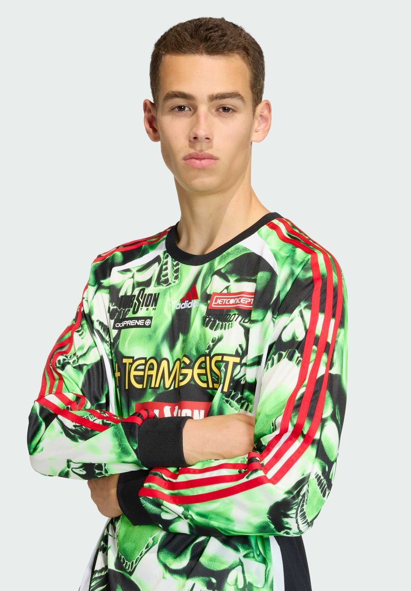 Lange mouw trui in zwart, groen en rood met een graffiti-achtig patroon. Voorzien van rode strepen op de schouders en een logo op de borst.