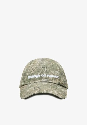 Cappellino da baseball mimetico verde con visiera curva e testo ricamato bianco "feelings on repeat" sul pannello frontale.