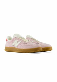 Ljust rosa mockaskor med krämfärgade detaljer, en gummisula och en logotyp på sidan. Har en snörningsdesign och perforerade detaljer.