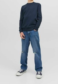 Mörkblå sweatshirt med ribbade mudd och nederkant, kombinerad med ljusblå rivna jeans och mörkblå mönstrade sneakers. Avslappnad passform, enkel design.