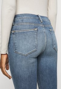 Jeans de mezclilla azul desvanecido con una cintura de altura media, que cuentan con bolsillos traseros, costuras en contraste y un ligero estiramiento para mayor comodidad.