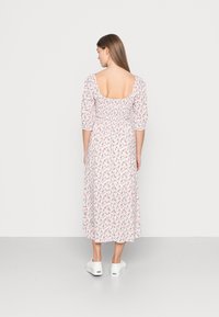 Vestido maxi floral em branco com padrões em rosa e verde. Possui um decote quadrado, mangas curtas balonê e uma cintura ajustada.