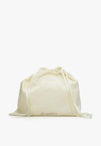 Worek ze sznurkiem w miękkim kremowym materiale, o zaokrąglonym kształcie, z dwiema białymi sznurkami i wytłoczonym logo na dole. Gładka tekstura.