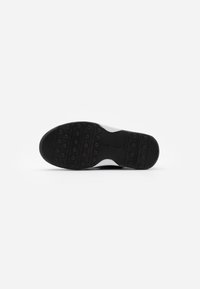 Suela de goma negra con patrón de agarre circular y detalles texturizados, con una sección superior blanca. Vista inferior de un diseño de bota.