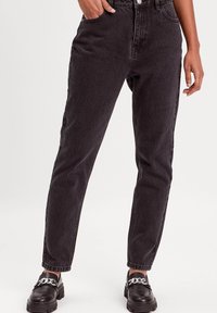 Jeans in denim nero a vita alta con una vestibilità dritta, tessuto testurizzato, tasche frontali e dettagli di cucitura a contrasto.
