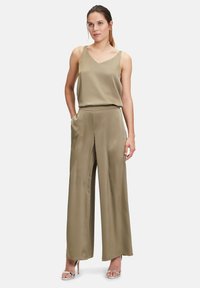 Oliwkowy satynowy top z dekoltem w kształcie V i cienkimi ramiączkami, zestawiony z szerokimi spodniami w dopasowanym materiale. Oba elementy charakteryzują się gładką teksturą.