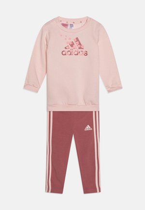 Felpa rosa chiaro con maniche lunghe e logo floreale di adidas; abbinata a leggings rosa scuro con strisce bianche laterali e logo.