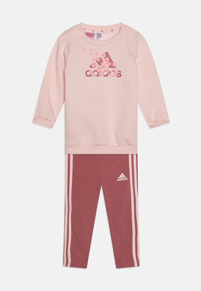 Felpa rosa chiaro con maniche lunghe e logo floreale di adidas; abbinata a leggings rosa scuro con strisce bianche laterali e logo.