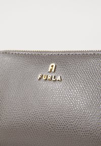 Cumpărătură din piele texturată gri, cu fermoar și detalii din aur, având logo-ul „A FURLA” embosat pe partea din față.