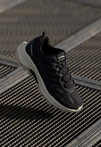 Black hiking shoe with a mesh upper, reinforced toe cap, and textured rubber sole. Features logo and lacing system for secure fit.