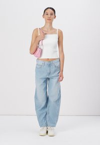 Biely rebrovaný crop top, svetlomodré široké nohavice a biele tenisky, skombinované s malou ružovou kabelkou. Jednoduchý dizajn a neformálny vzhľad.