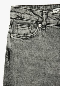Zwart-witte denim jeans met een hoge tailleband, voorzakdetails en zilveren hardware accenten. De stof heeft een gestructureerde afwerking.