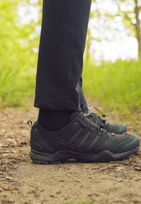 Czarne buty wędrówkowe o teksturowanej powierzchni, z materiałów syntetycznych i gumowymi podeszwami. Posiadają system sznurowania oraz wzmocnione akcenty.