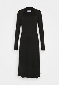 Černé jemně žebrované midi šaty s dlouhými rukávy, hranatým výstřihem, přiléhavým pasem a mírný rozšířením na lemu. Měkká textura, bez viditelných vzorů nebo akcentů.