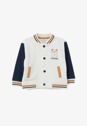 Chaqueta de algodón blanca con mangas en color marino, acentos en color beige y bordado de un oso en el pecho. Presenta un collar acanalado, puños y botones a presión.