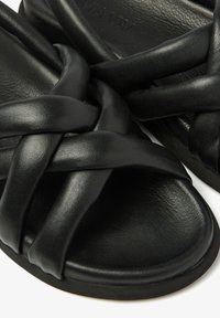 Zwarte leren sandalen met een gevlochten bandontwerp en een gestructureerde voetbed, met een ronde vorm en een glad oppervlak.