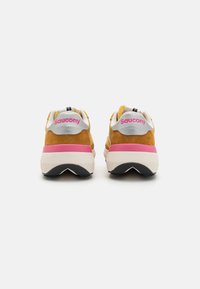 Saucony sneakers with a yellow suede upper, white and pink accents, black outsole, and logo on the heel. Cushioned tongue and collar.