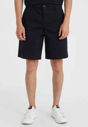 Marineblauwe katoenen shorts met een rechte snit, zijzakken en een knoopsluiting. Gecombineerd met witte sneakers met zwarte accenten.