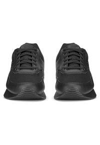 Čierne športové topánky s hladkým syntetickým zvrškom, sieťovanými panelmi, plochými šnúrkami a textúrovanou gumovou podrážkou. Minimalistický dizajn, žiadne viditeľné logo.