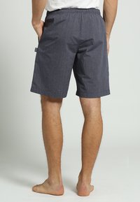 Mannenshorts in marineblauwe strepen van lichtgewicht stof, met een elastische tailleband en twee zijzakken, ontworpen voor comfort en functionaliteit.