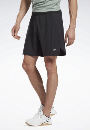 Zwarte sportshorts met een elastieken tailleband en zijslitsen. Bevat een subtiele logo in zilver. Draagt met witte sneakers en een licht shirt.