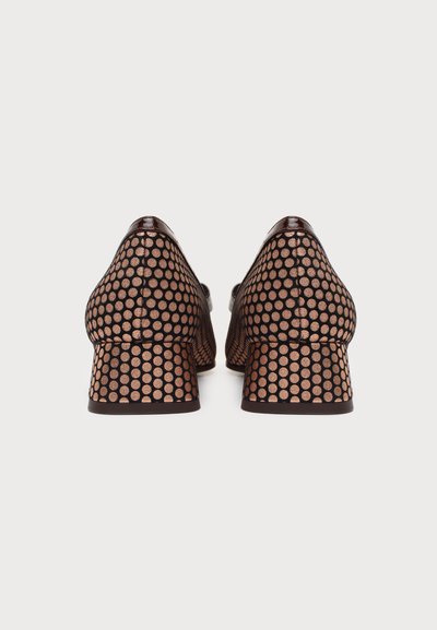 Paire de chaussures à talons bas pour femmes avec des pois métalliques couleur rose doré sur une base noire, vues de dos sur un fond uni.
