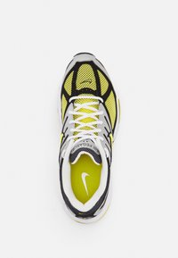 Sapatos Nike Air Pegasus, com um cabedal em malha amarela, detalhes em preto e prata, atacadores brancos e uma sola texturizada.