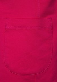 Tissu en coton fuchsia présentant une poche plaquée arrondie avec des coutures assorties. Texture lisse sans motifs ni accents visibles.