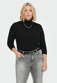 Črna turtleneck pulover z dolgimi rokavi, gladke teksture. Usklajeno s sivimi kavbojkami in črnim pasom s okroglo zlatim sponko.