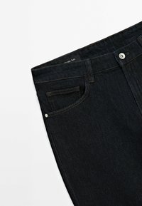 Ciemnoniebieskie dżinsy z denimu o gładkiej fakturze, z zapi�ęciem na guzik i zamek, szlufkami na pasek oraz przednią kieszenią.