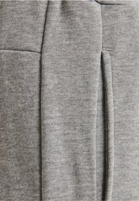 Šedá mikina s jemnou texturou, s bočním rozparkem a viditelným šitím. Materiál má mírný melírovaný vzor.