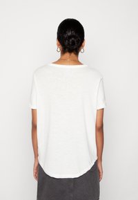 Weißes T-Shirt mit kurzen Ärmeln aus leichtem Stoff, mit Rundhalsausschnitt und leicht gewölbtem Saum, von hinten gezeigt.