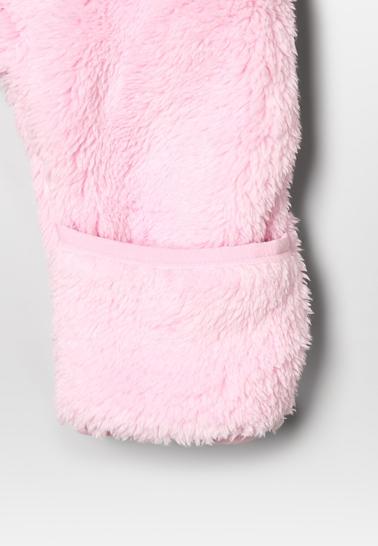 Tela de color rosa suave y esponjosa con una superficie texturizada, que presenta un puño suave y elástico. El diseño incluye un bolsillo integrado en la manga.
