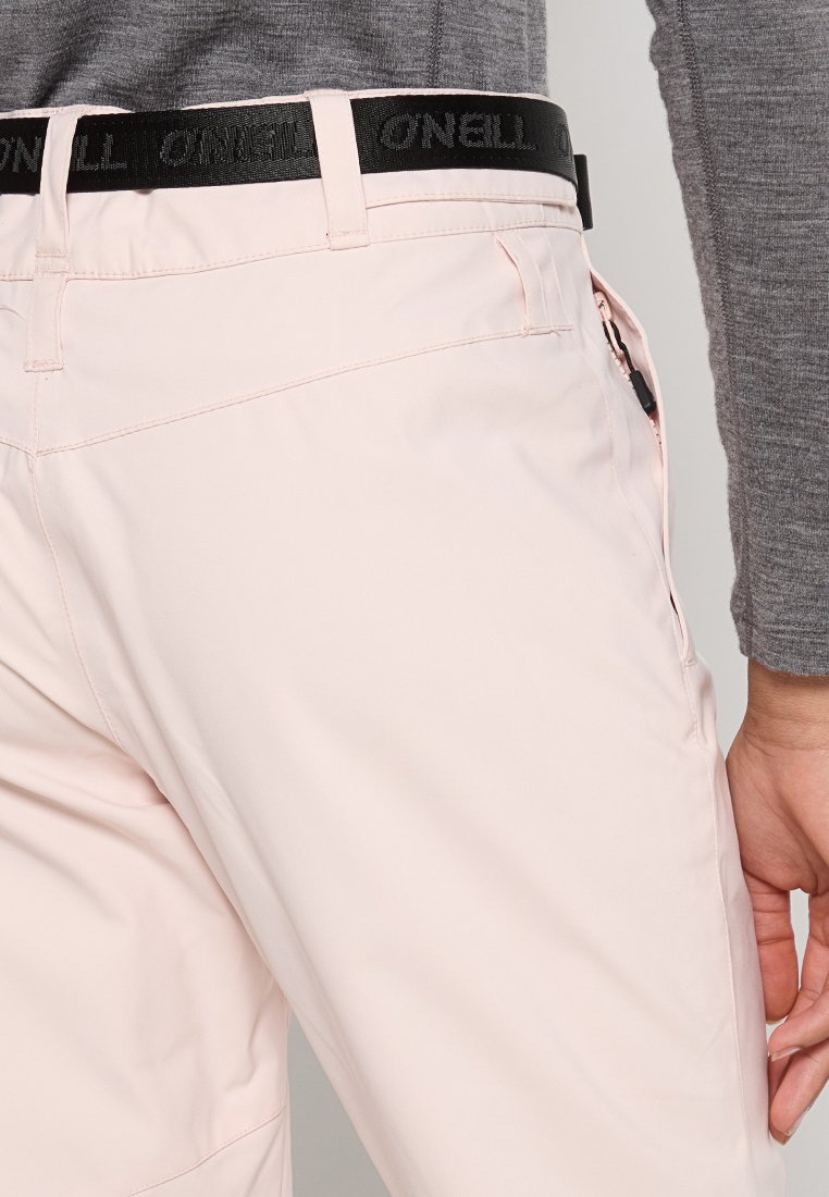 Jasnoróżowe spodnie z czarnym paskiem O'Neill, wyposażone w kieszeń na zamek błyskawiczny i gładką teksturę. Widok z boku pokazujący dopasowany krój i szwy.
