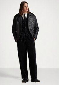 Svart skinn motorsykkeljakke, hvit skjorte, svart vest og vide svarte bukser; slankt design med glatt tekstur, skreddersydd passform.