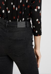 Svarta högmidjade jeans med en strukturerad denimfinish. Funktioner inkluderar bakfickor och ett lädermärke med präglingen "ONLY".