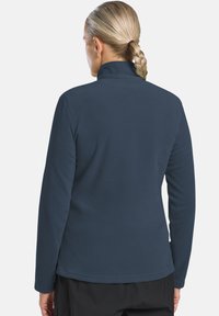 Marineblaue Fleecejacke mit hochgeschlossenem Kragen und langen Ärmeln. Glatte Textur und eine leicht taillierte Passform. Hüftlang mit geradem Saum.