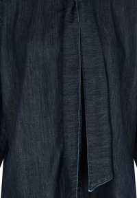 Chemise en denim bleu foncé avec une finition texturée. Présente une ouverture fendue à l'avant, des coutures soignées et un détail de col rabattu.