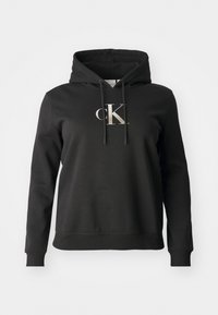 Felpa nera con cappuccio realizzata in un materiale morbido, con tasca frontale, cordini e un logo 'CK' metallico sul petto.
